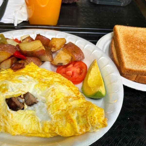 Breakfast plate with a cheese omelet, roasted potatoes, tomato, avocado, toast, and a side of salsa.