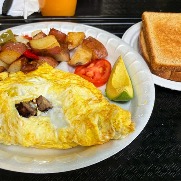 Breakfast platter with a mushroom omelet, roasted potatoes, tomato, avocado, toast, and salsa on a serving tray.